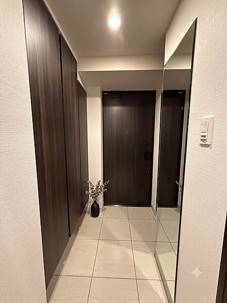 落ち着いた木目調の大型シューズボックスと姿見を完備した、気品漂う玄関スペース。※家具や装飾はCG画像となり販売対象には含まれません。