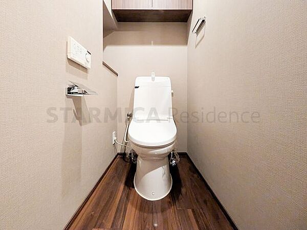 温水洗浄便座付きトイレ。吊戸棚にトイレットペーパーやお掃除道具などもスッキリ収納可能です。