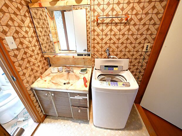洗面室。レトロな柄の壁紙がオシャレです。洗濯機置場も室内にございます。