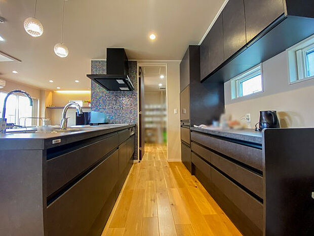 スタイリッシュなデザインのペニンシュラキッチン。キッチンに合わせた造作カップボードあり。食器類や家電類をまとめてスッキリ収納可能。