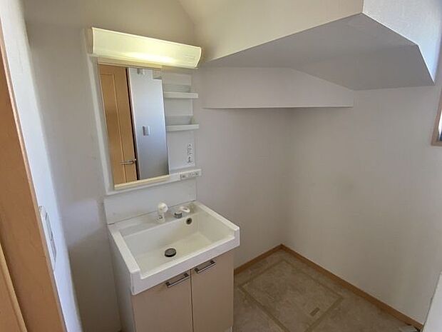 階段下のデッドスペースを利用した洗面所です。棚付きの洗面台です。