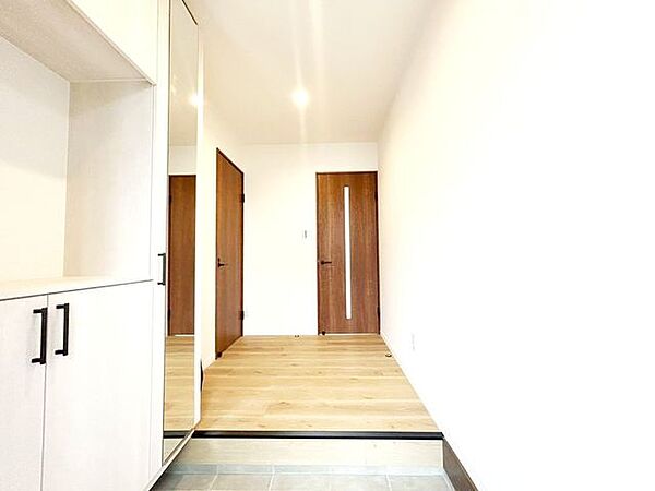 【リフォーム済み】玄関ホールの写真です。玄関タイルを張替え、ホールの床はフロアタイル張り、玄関収納を交換しました。正面がリビングへの扉、左手が洗面脱衣場への扉になります。