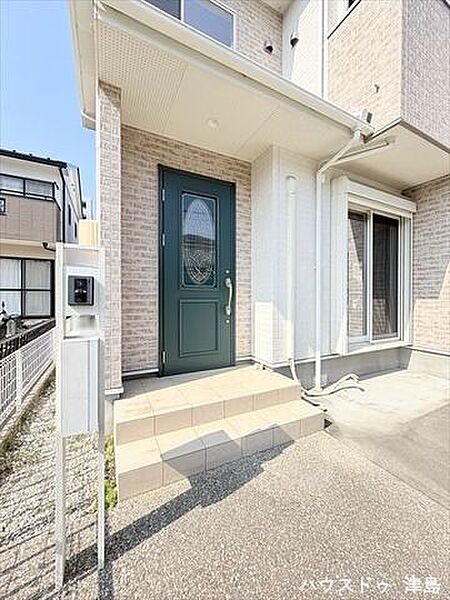 玄関ポーチは照明付きで暗い時間帯の帰宅も安心。表札・インターホン・ポストが一体型になった門柱。