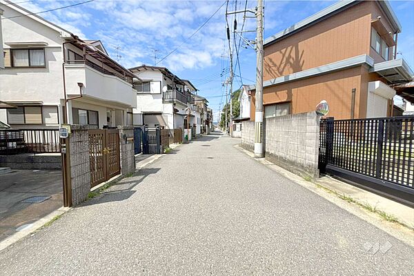 物件の南東側前面道路（南西側から）周辺は一戸建てと集合住宅が混在する住宅地。田畑が点在し、のどかな雰囲気。東側には『陸上自衛隊川西駐屯地』があります。［2026年7月10日撮影］