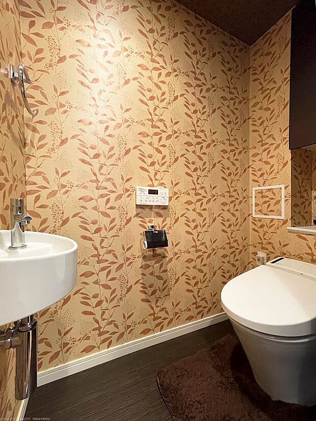 トイレは手洗い器別、タンクレス仕様。落ち着いた暖色系の壁紙にされています。