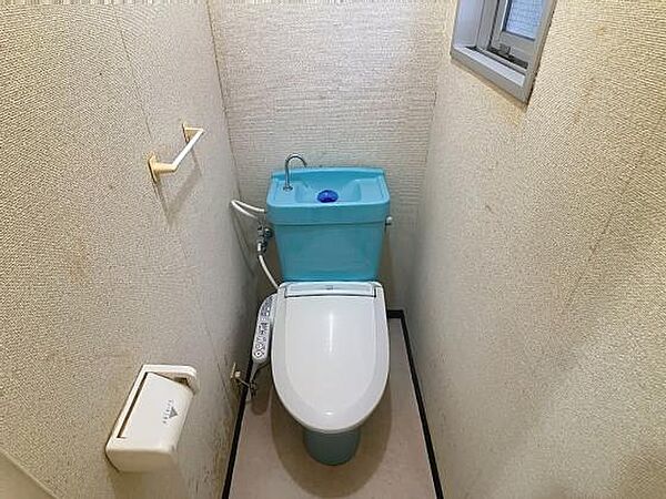 スカイブルーのタンクが目を引く、温水洗浄便座付きのトイレ。小窓があり換気も良好です。