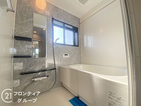 大きな窓から自然光が差し込む、開放感あふれるバスルームです　木目調の壁がリラックスタイムを優雅に演出します　一日の疲れを癒やすプライベートな空間として、至福のひとときをお過ごしいただけます