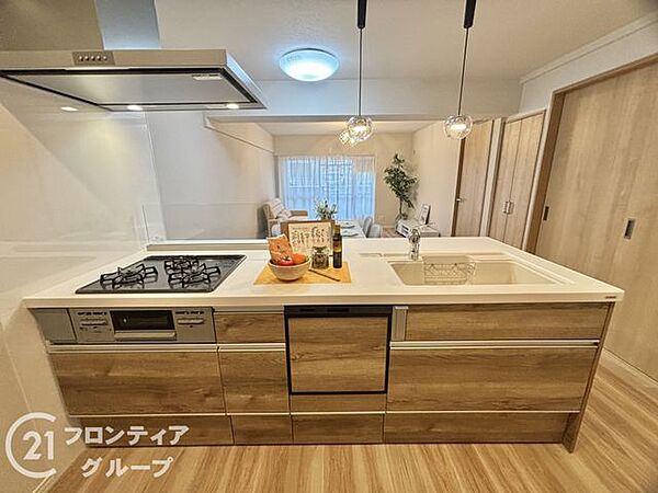 木目調のデザインが空間に溶け込む上質なキッチンですね。機能的な3口コンロや食器洗浄乾燥機を備えており、毎日の家事時間を豊かなひとときに変えてくれる設備が整っています