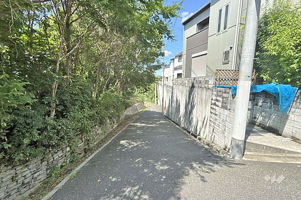 物件の西側前面道路（南側から）［2026年8月4日撮影］周辺は一部店舗や事務所、主に一戸建てと集合住宅が並ぶ住宅地です。
