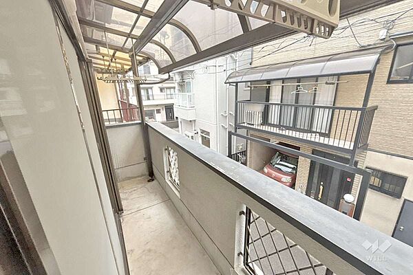 南西側バルコニー［2026年8月3日撮影］周辺は店舗や事務所が混在し、主に一戸建てや集合住宅が立ち並ぶ住宅地です。
