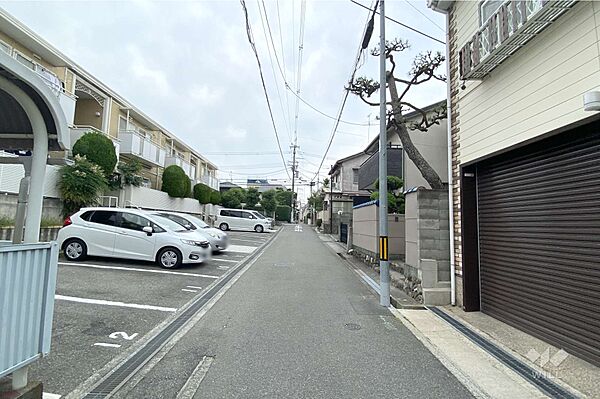 物件の南側前面道路（東側から）［2025年6月8日撮影］。阪急宝塚線「曽根」駅徒歩7分。シャッター付きのガレージあり（並列駐車2台可）