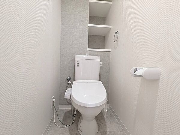 清潔感のあるホワイトとグレーを基調としたトイレ空間。オープンシェルフは、お好みの小物を飾って彩りを添えることができます。快適な温水洗浄便座付きです。