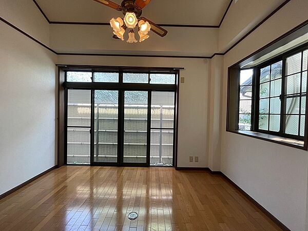 光が差し込む広々とした居室。ウッドフローリングと落ち着いた色の建具が調和し、多様な家具配置が可能です。