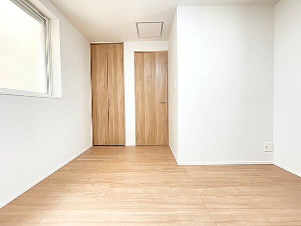 自然光が差し込む明るい室内。クローゼットとドアが統一された木目で、心地よい空間を演出します。