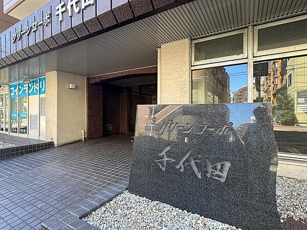 「グリーンコーポ千代田」の物件です。エントランスには、マンション名の入った石碑があり、入り口横にはコインランドリーも併設されています。