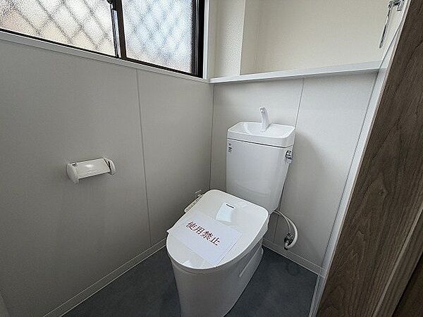 小窓から光が差し込む、明るいトイレ空間。収納棚も備え付けられ、機能性も兼ね備えています。清潔感あふれる空間で、日々の暮らしを快適に。