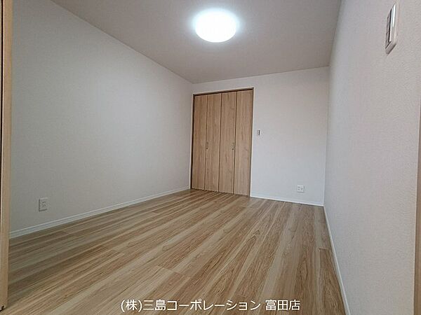 明るい木目調のフローリングが特徴的な居室は、収納も備え付けられています。シンプルで使いやすい空間です。