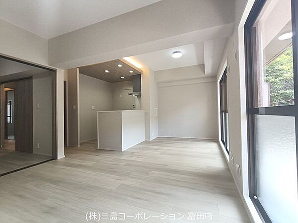 木目調の天井とダウンライトが映える、明るく開放的なリビング。キッチンとの一体感が魅力の空間です。