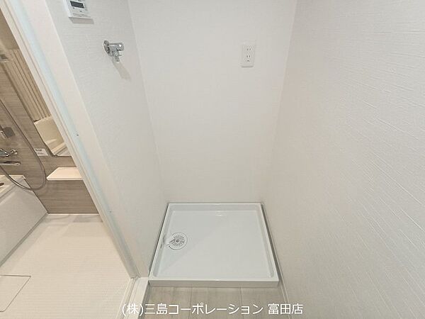 洗濯機置き場は、防水パンが設置されており、万が一の水漏れにも配慮されています。コンセントも完備で、機能的な空間です。