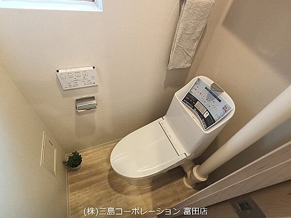 清潔感のある白い便器と、温かみのある木目調のフロアが調和したトイレ空間。小窓からの採光も心地よく、快適にお過ごしいただけます。