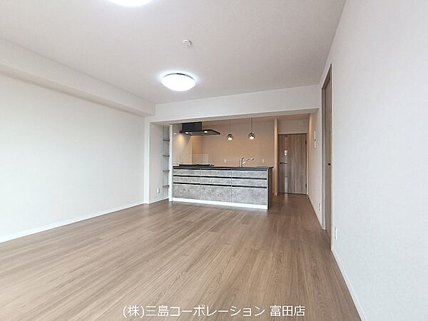 明るい木目調のフローリングが心地よいLDK。リビングでくつろぎながら、開放的なキッチンで料理を楽しめます。