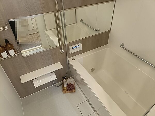 落ち着いた色合いの壁と浴槽が調和する浴室です。手すりが設置されており、安全に配慮した設計がうかがえます。一日の疲れを癒すバスタイムをお過ごしください。
