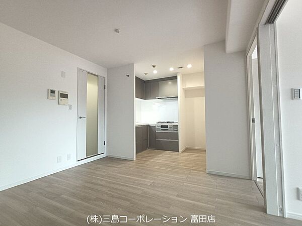 明るい木目調の床と白い壁が調和し、開放感のあるリビング。キッチンへの動線もスムーズで、快適な暮らしが叶います。