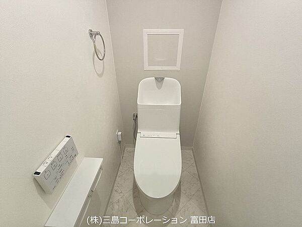 清潔感あふれる明るいトイレ。温水洗浄機能付きで快適にお使いいただけます。手洗いカウンターと収納もあり、機能性も兼ね備えています。