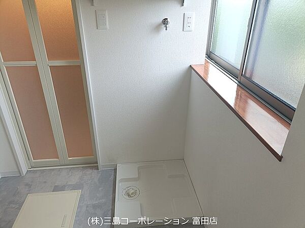 窓から自然光が差し込む明るい洗面所。洗濯機置き場も確保されており、機能的な空間です。