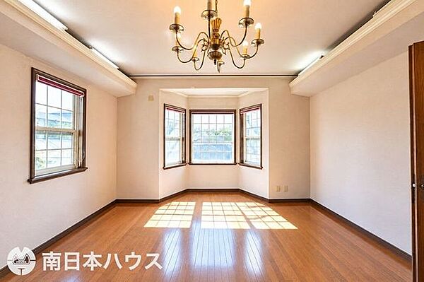 複数の窓を備え、明るく開放的なリビング。シャンデリアが空間に上品な趣を添えています。