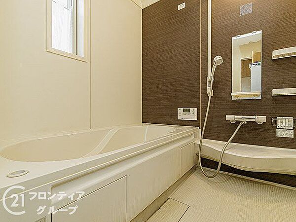 木目調のアクセントパネルが落ち着いた空間を演出する浴室です。ゆったりとした浴槽で一日の疲れを癒やすリラックスタイムを過ごせます。鏡や棚も使いやすい位置に配置された機能的な設計です