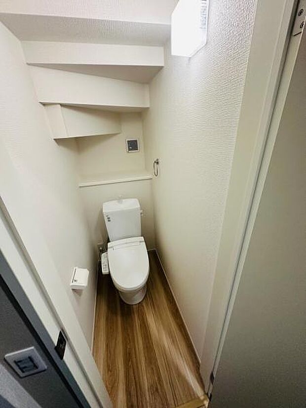 階段下を活用したトイレ空間。天井の高さはないものの、収納棚もあり十分満足な空間です。
