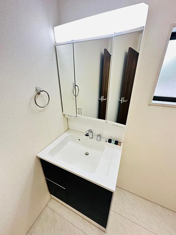 2号棟 明るい照明のついた洗面台。3面鏡仕様で身支度も整います。