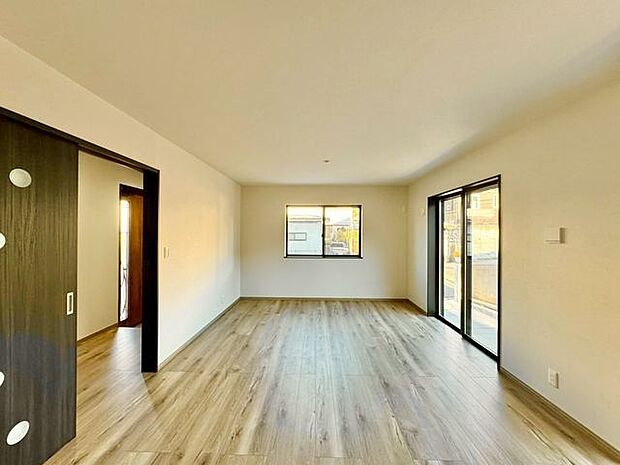 ナチュラルな木目調の床から木のぬくもりを感じられる広々としたリビングルーム。