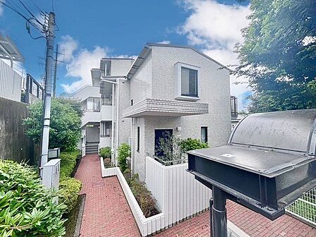 閑静な住宅街に佇む重厚感のある低層マンション。ゆったりと落ち着いた時間をお過ごしいただけます。（空の加工を生成AIで行っています）