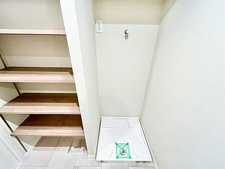 洗面台の背面に洗濯機置場をご用意。リネン類の置場に便利な収納棚が備わっています。
