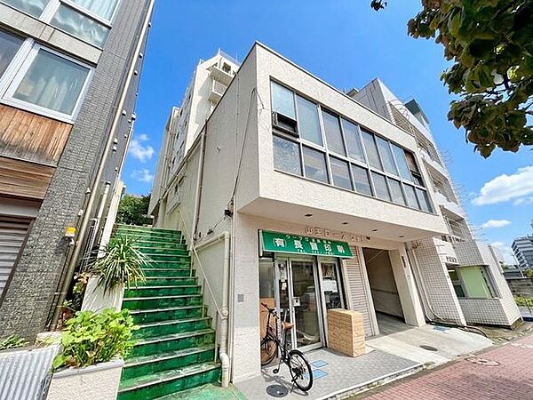 街に溶け込むオフホワイトの外観にグリーンのコントラストがアクセント。（空の加工を生成AIで行っています）