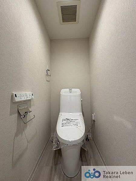 ウォシュレット機能付きのトイレは壁掛けリモコンの上位グレードを採用。便座がスッキリした印象となり、限られた空間を広く見せる効果があります。