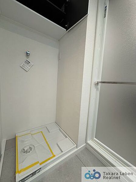 洗濯機置場。収納棚が設置されている為、洗剤類の収納場所としてお使いいただけます。