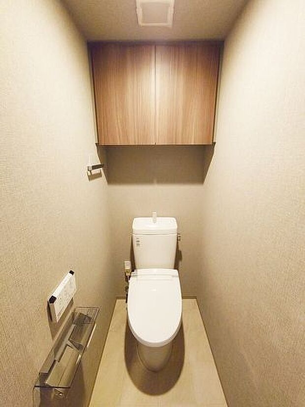 上部に吊戸棚がある温水洗浄便座付トイレ。ペーパーホルダーには2ロール設置可能です。