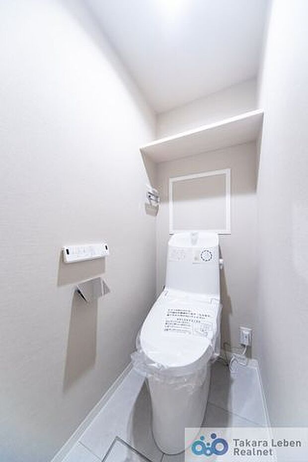 落ち着いた壁紙で清潔感のあるトイレ。トイレットペーパーホルダーとタオル掛けは標準で実装してます。上部に棚があり、掃除用具などの収納場所に困りません。
