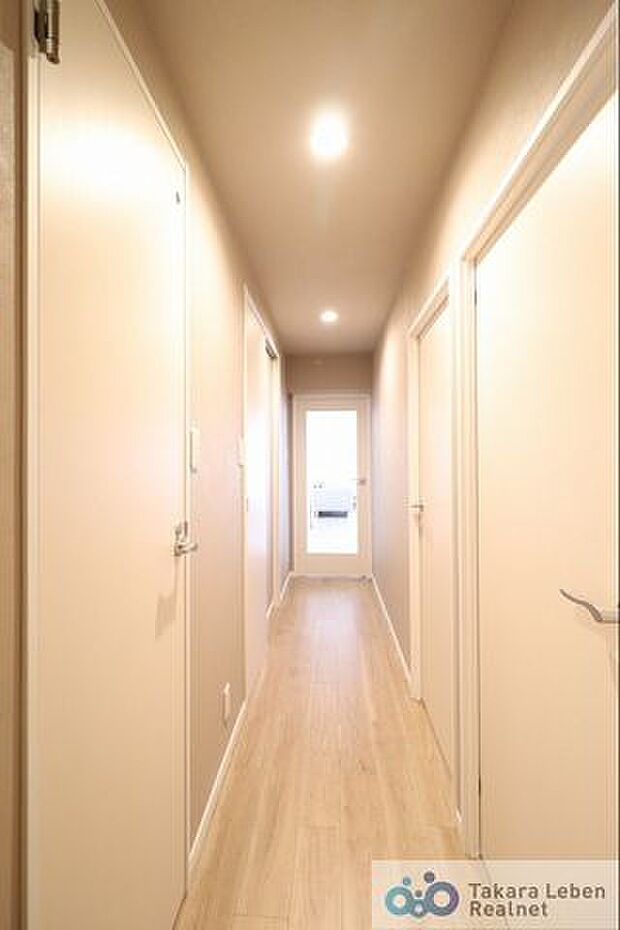 暖色のダウンライトが優しく照らす廊下。建具を白にすることで圧迫感のない空間に。