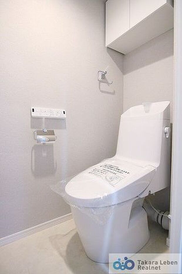 ウォシュレット機能付きのトイレは壁掛けリモコンの上位グレードを採用。上部には吊戸棚があるので、トイレットペーパーのストックや清掃道具等を収納するのに便利です。