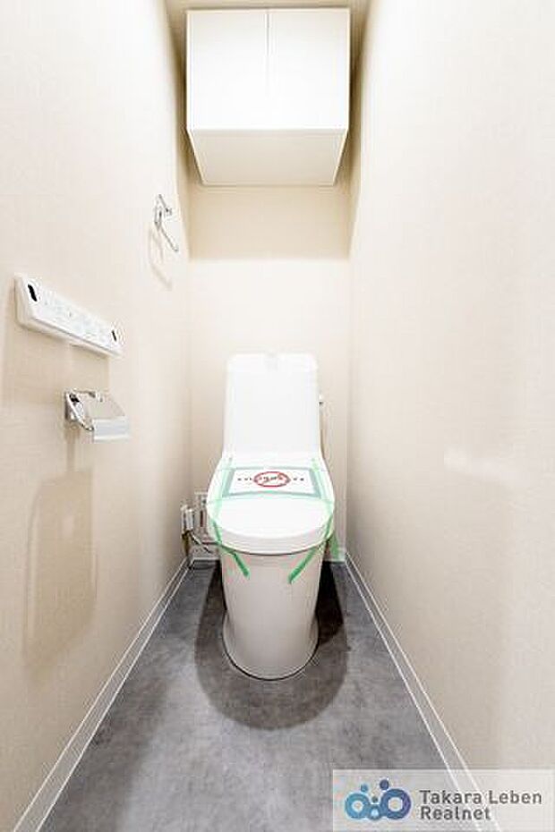 吊戸棚付き温水洗浄トイレ。リモコンは操作がしやすい壁掛けタイプです。