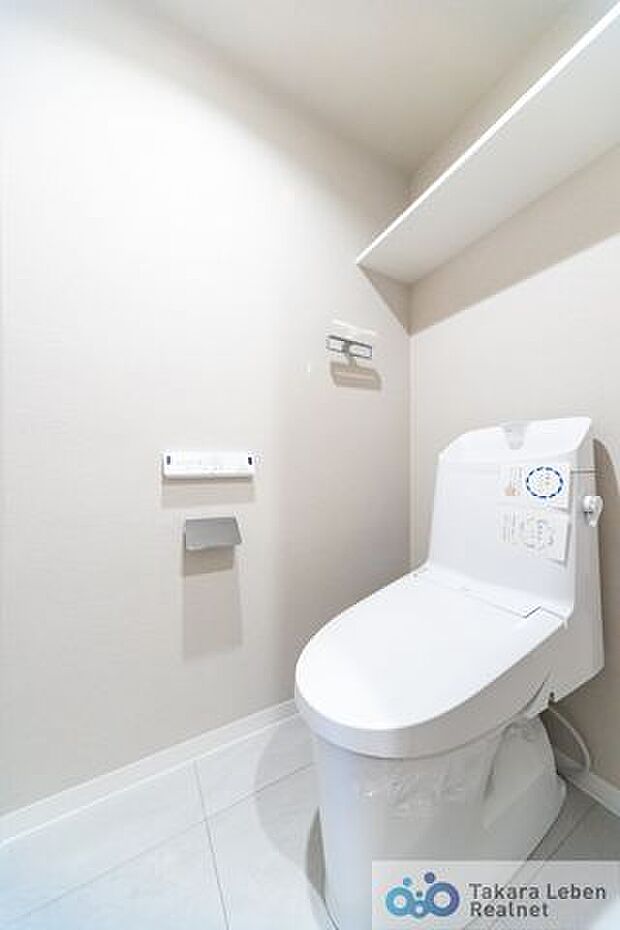 白を基調に清潔感のあるトイレ。トイレットペーパーホルダーとタオル掛けは標準で実装してます。上部に棚があり、掃除用具などの収納場所に困りません。