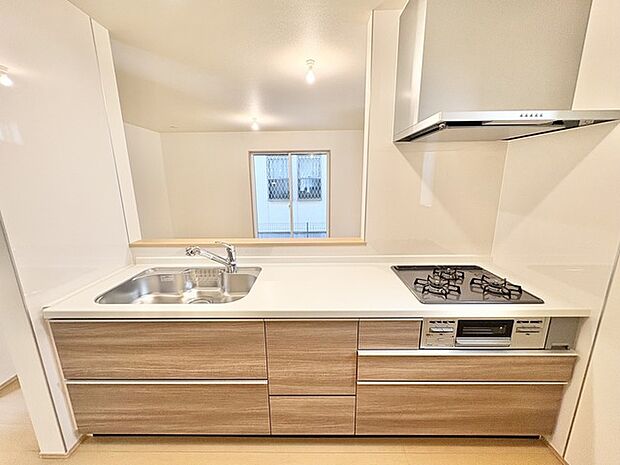 清潔感のある空間に、温かみのある木目調の収納が調和したキッチン