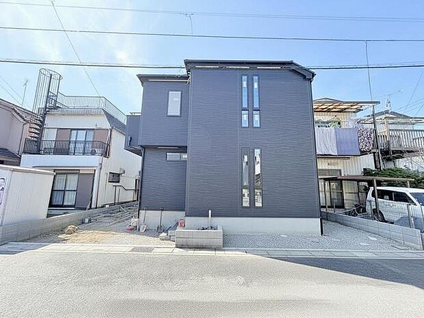 モダンな黒い外壁が、穏やかな空の下で洗練された佇まいを演出しています。