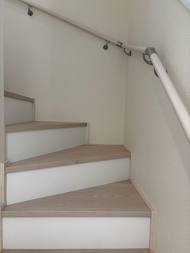 階段室。柔らかな色合いと手すりが、安心感のある空間を演出します。