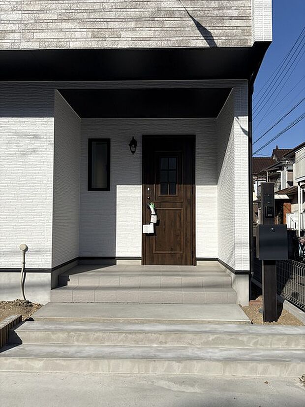 モノトーンの外壁に映える、温かみのある玄関扉がお出迎え。