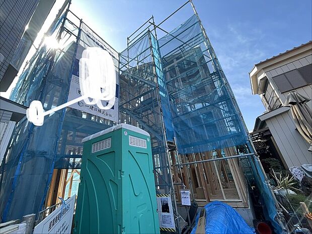 青いシートに包まれ、空へと伸びる木造建築の姿